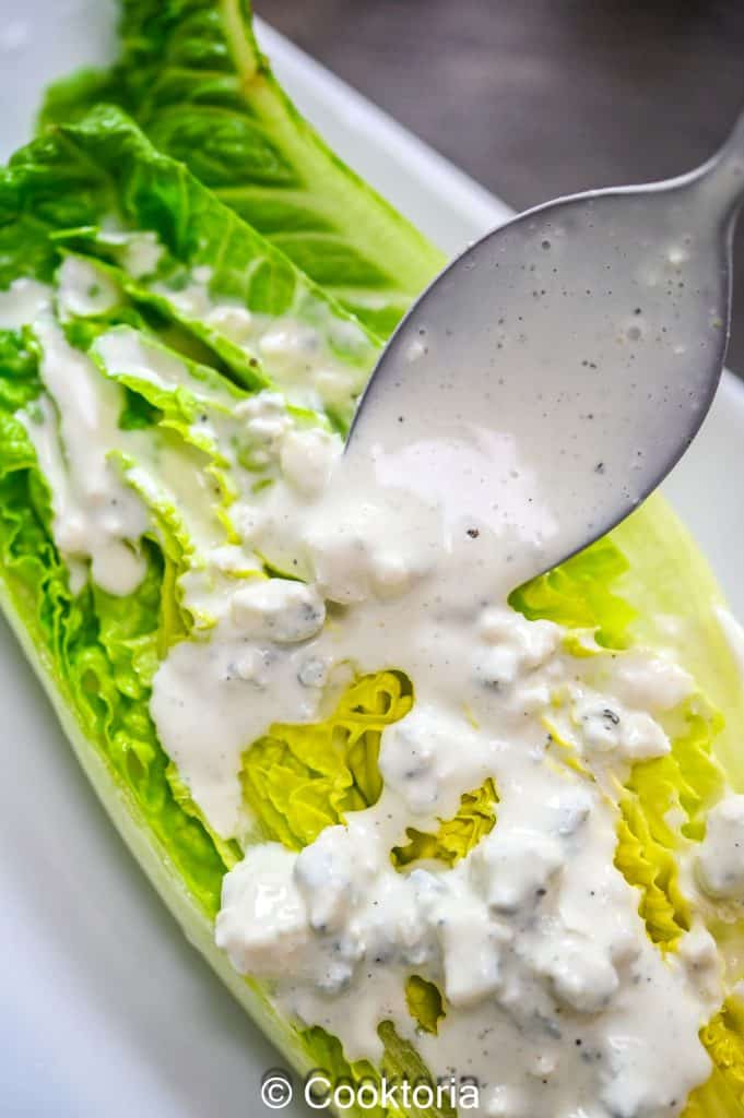 Pouring Blue Cheese Dressing on a lettuce